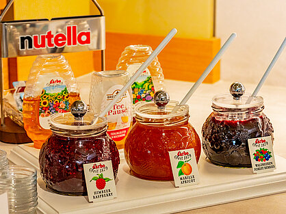 Konfitüren und Honiggläser mit Etiketten auf dem Frühstücksbuffet