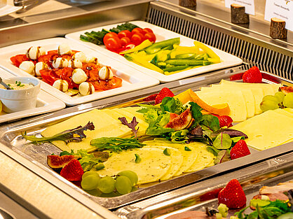 Käseplatte mit Obstgarnitur und frischem Gemüse am Frühstücksbuffet