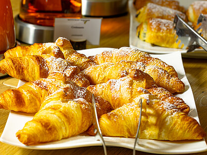 Frisch gebackene Croissants mit Puderzucker am Frühstücksbuffet