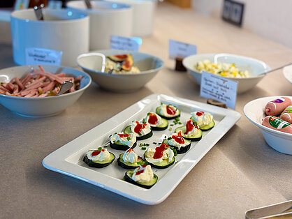 Gurkenscheiben mit Frischkäse und Paprika sowie hausgemachte Salate auf dem Frühstücksbuffet