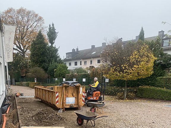 Blick auf den gefüllten Graben und den Dreck auf dem Parkplatz