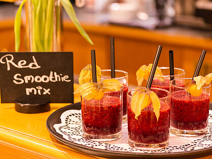 Roter Beeren-Smoothie mit Physalis und Strohhalm auf dem Frühstücksbuffet