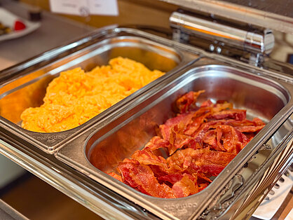Rührei und knuspriger Bacon in Buffetbehältern beim Frühstück im Hotel Birkenhof