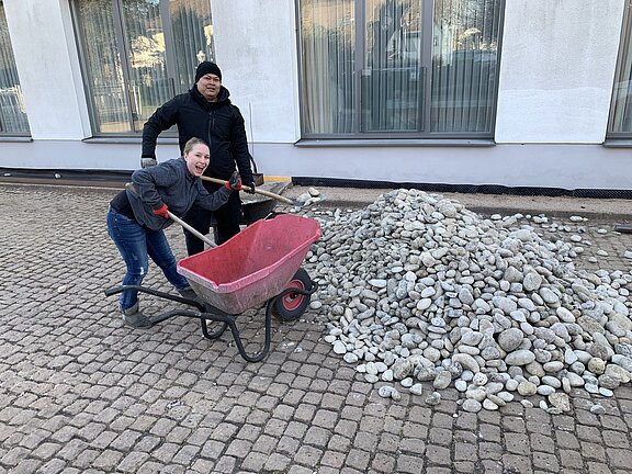 Sarah Spahn und Chaowalit Naboon helfen mit dem Kies